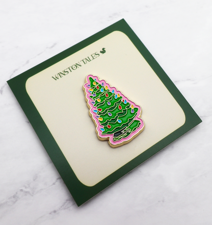 Christmas tree-themed magnetic enamel pin on a card with 'Winston Tales' branding on a marble surface